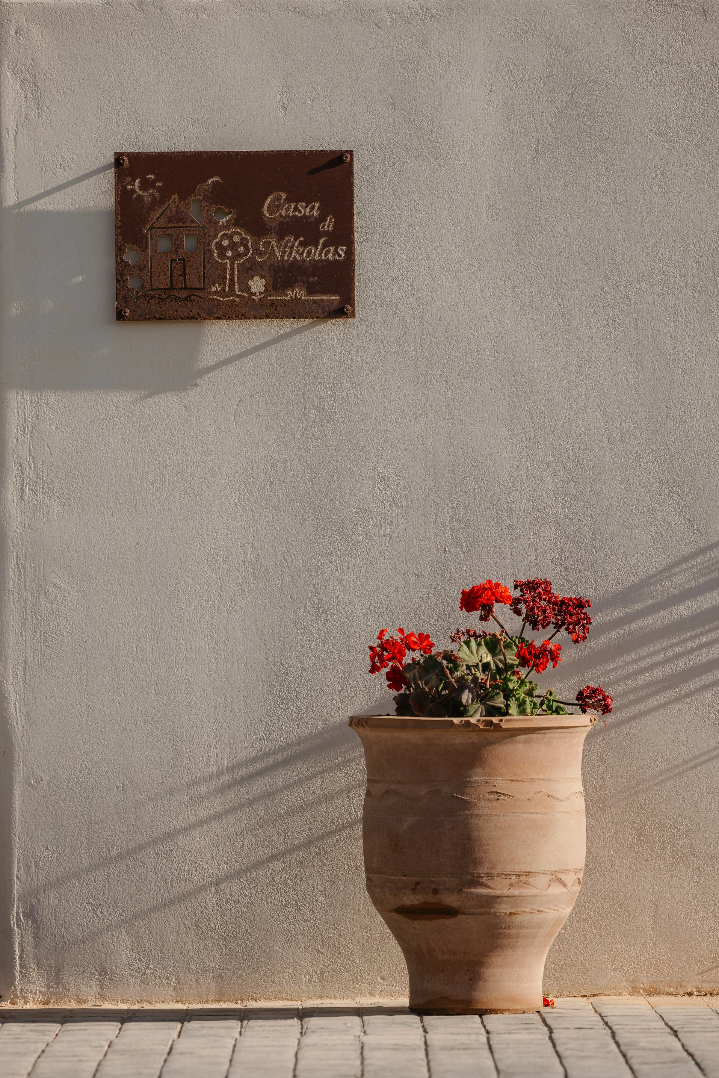 The nameplate and a geranium urn in warm light