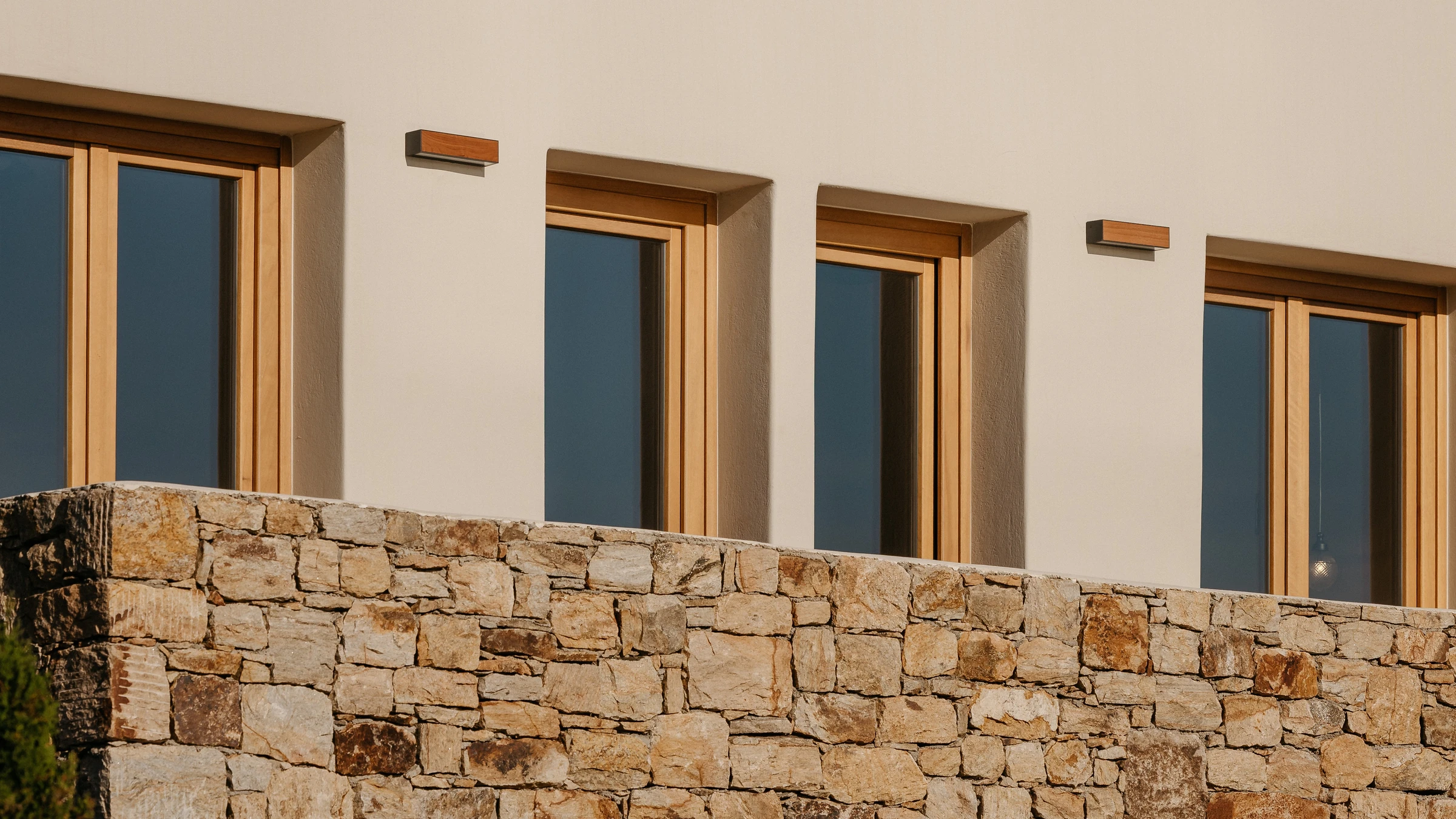 A row of timber windows above the dry-stone wall