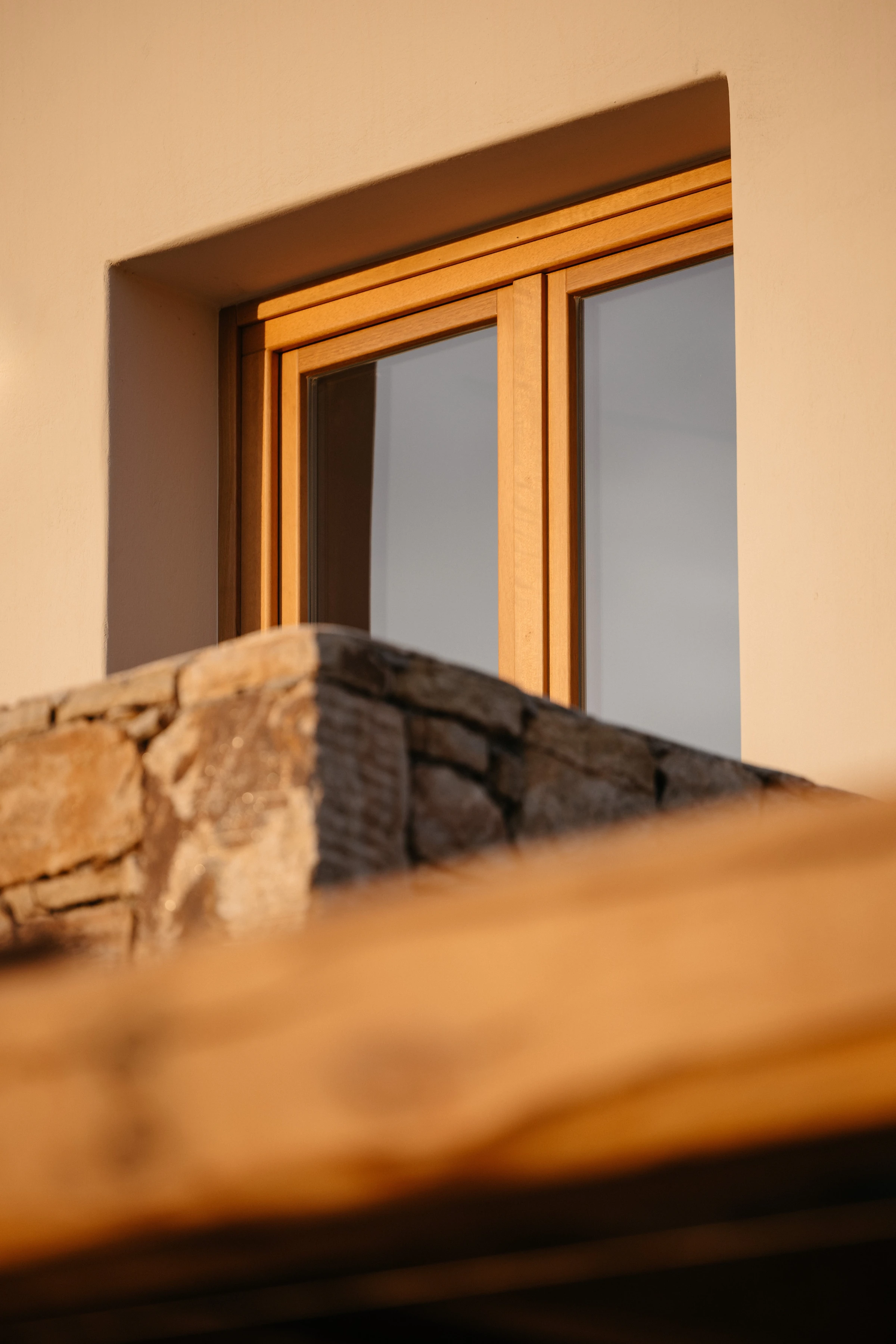 A timber window above stone, seen low in the sun