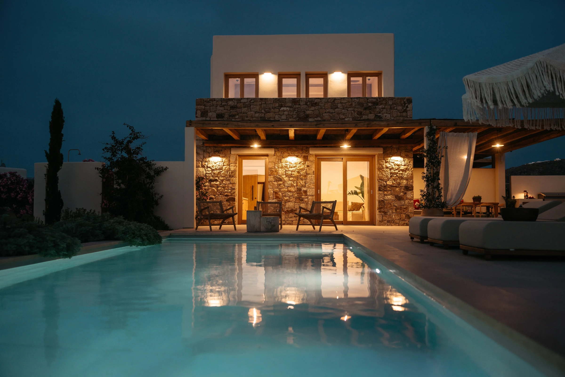 The house lit and reflected in the pool at night