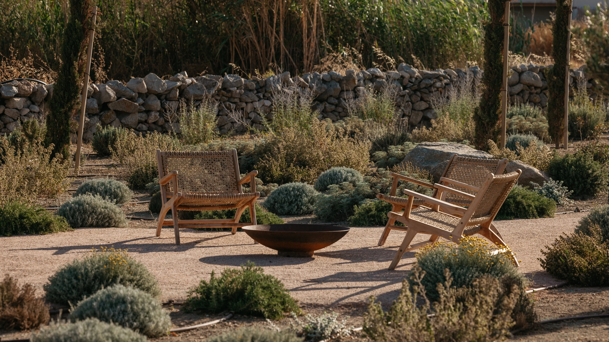 Woven chairs and a fire bowl in the dry garden
