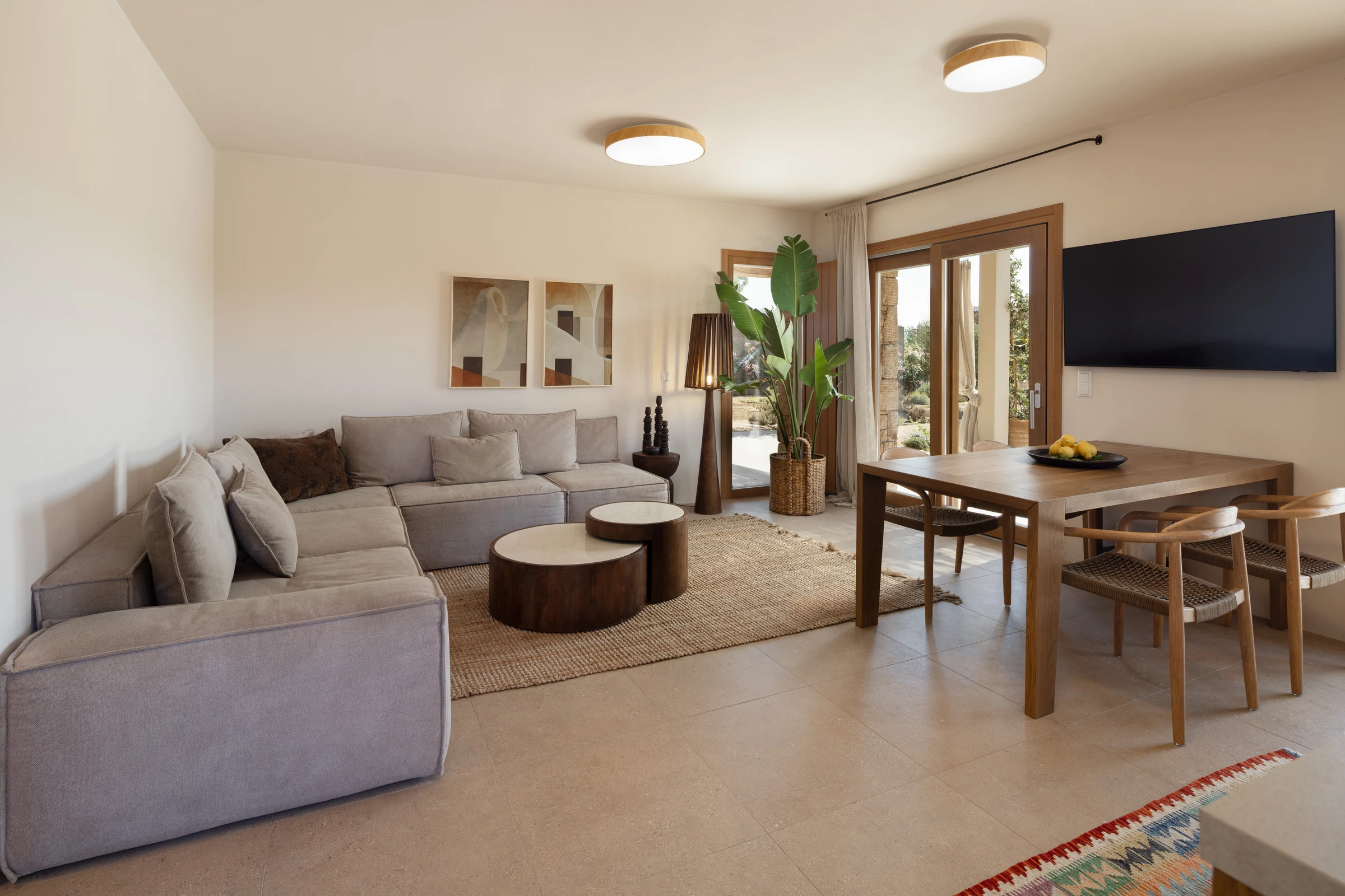 Wide living and dining room with L-shaped sectional and terrace doors
