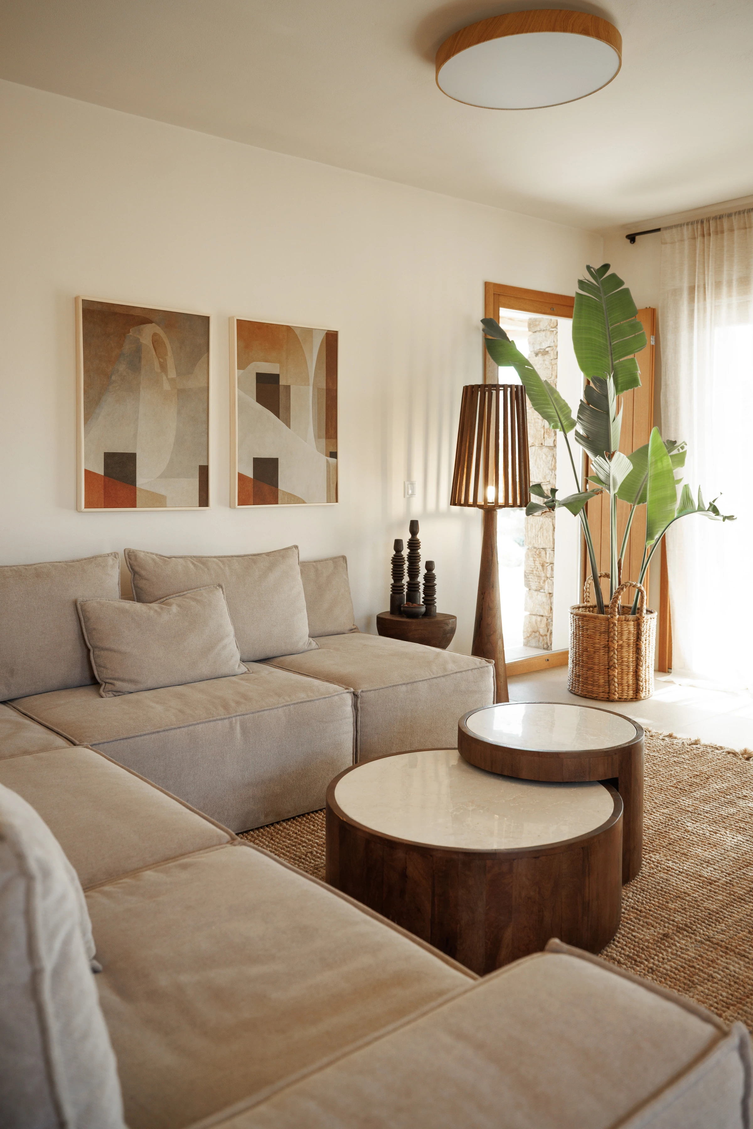 Living corner with sectional, round marble tables and floor lamp
