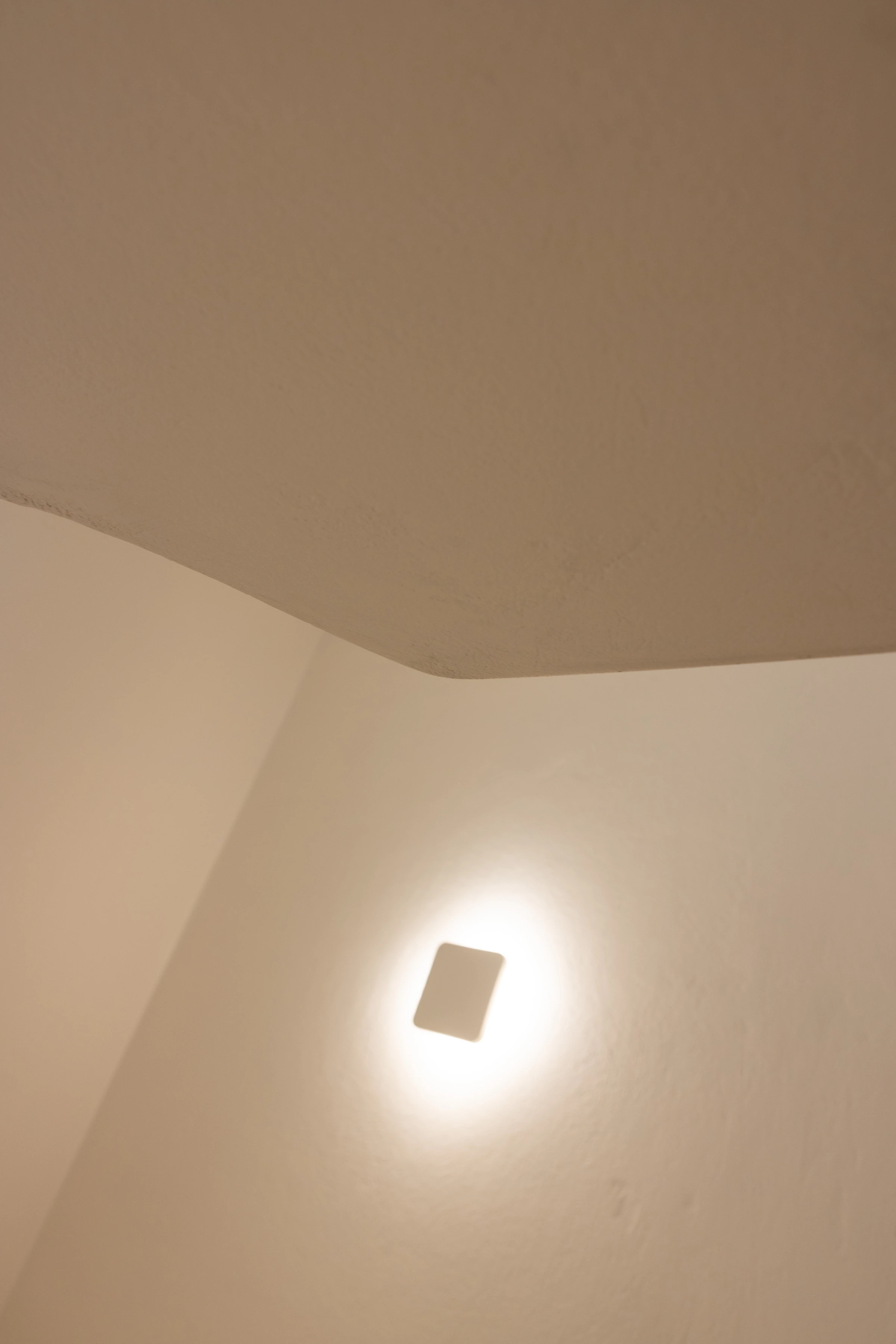 Recessed wall light glowing on a plaster corner beneath the ceiling