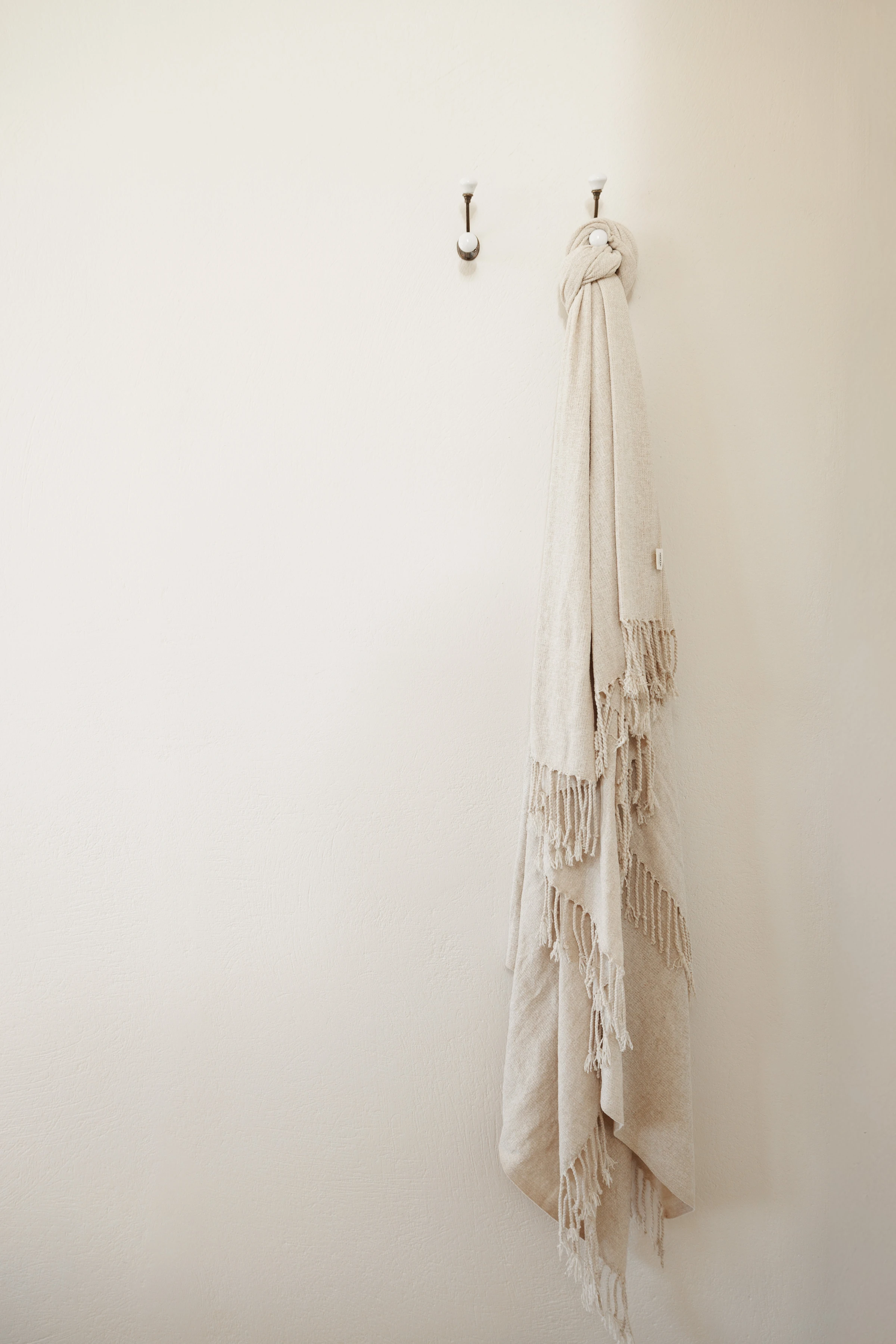 A linen fringed throw knotted on a ceramic wall hook