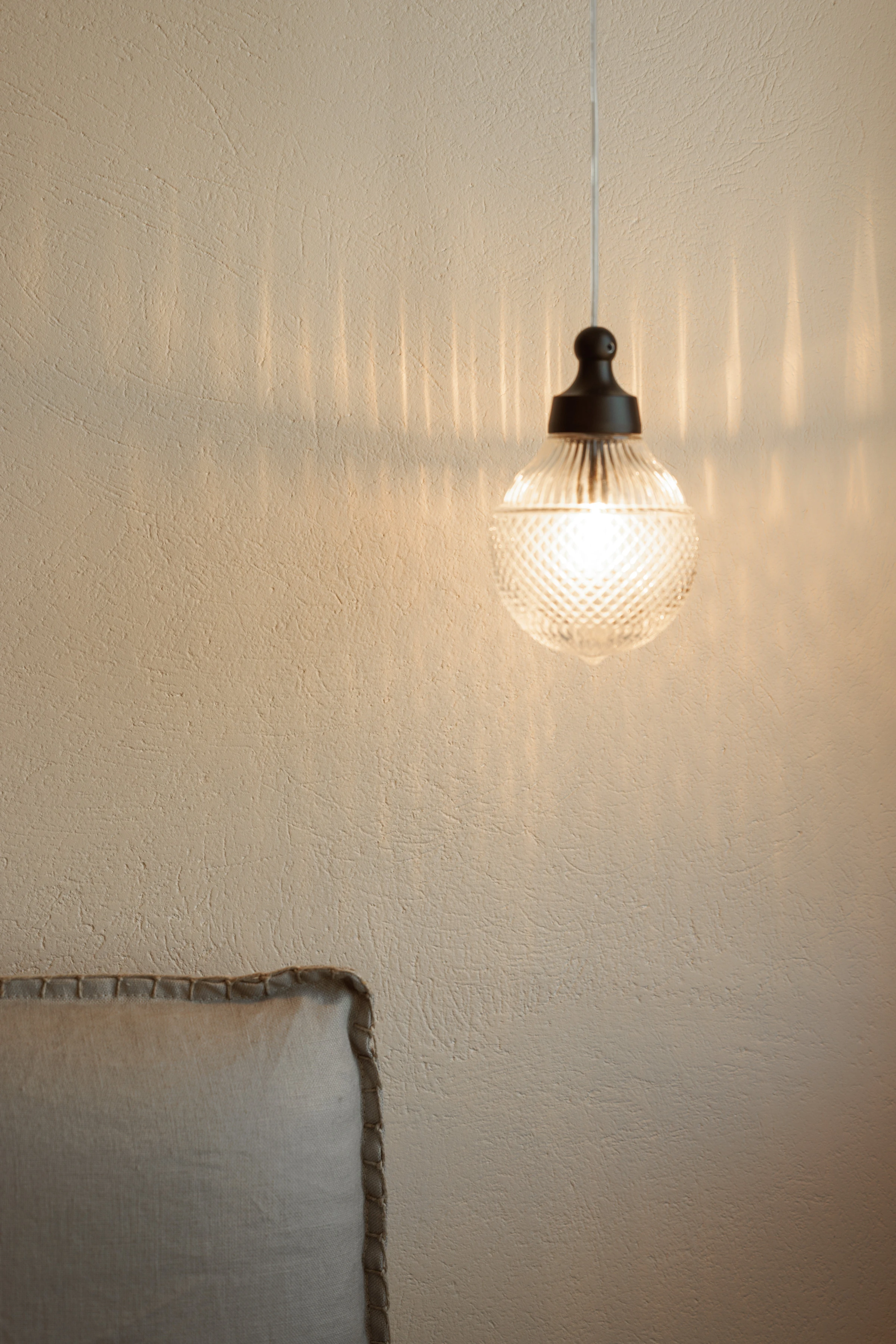 A cut-glass pendant lit against the plaster wall
