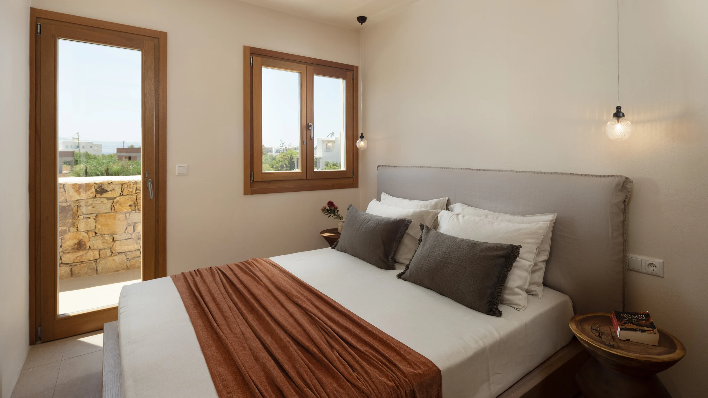 The second bedroom, terracotta throw and grey linen headboard by the terrace door