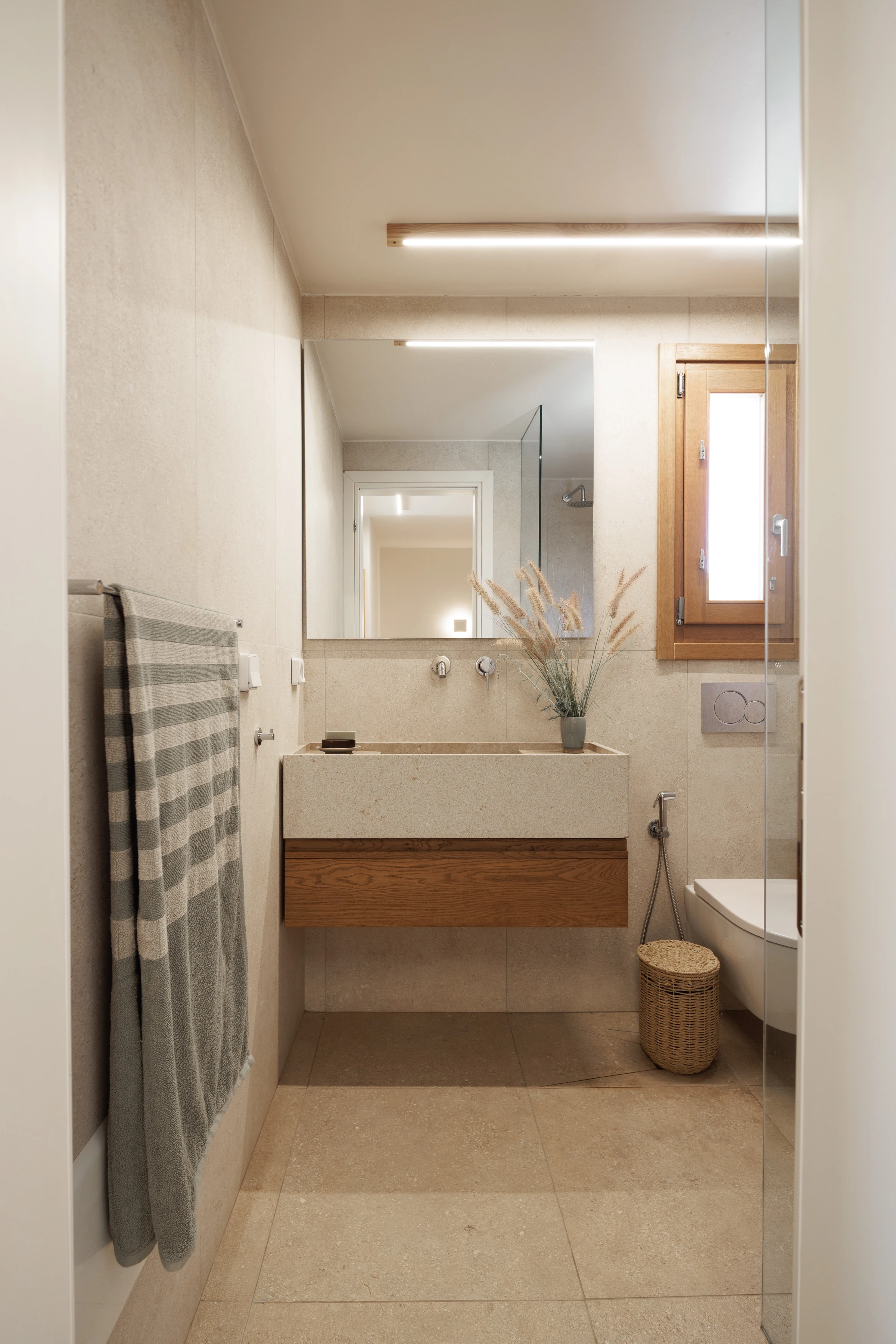The stone-basin bathroom: floating oak vanity, mirror and walk-in shower